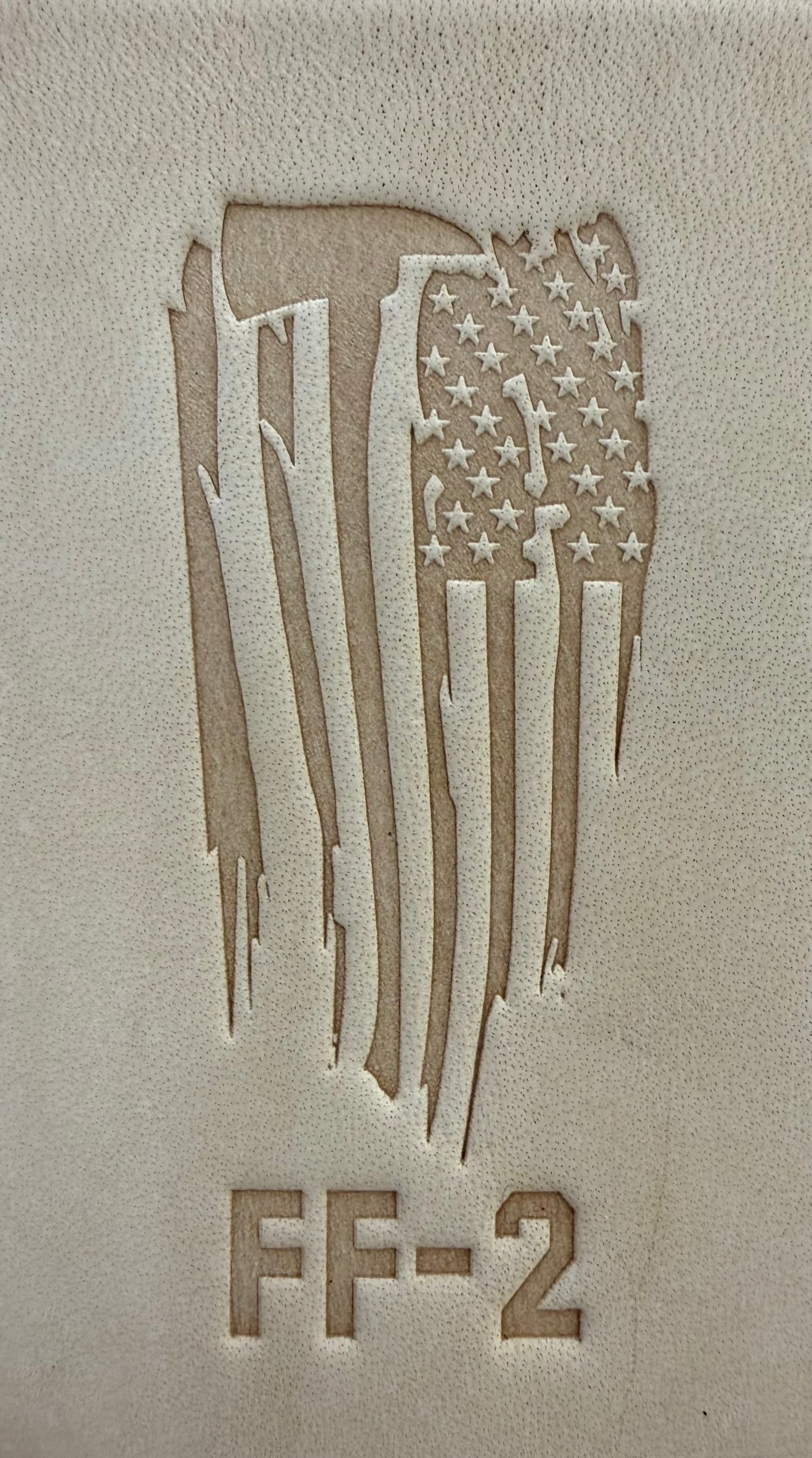 Delrin leather stamp pressing a tattered U.S. flag design with a firefighting axe and Halligan bar into leather.