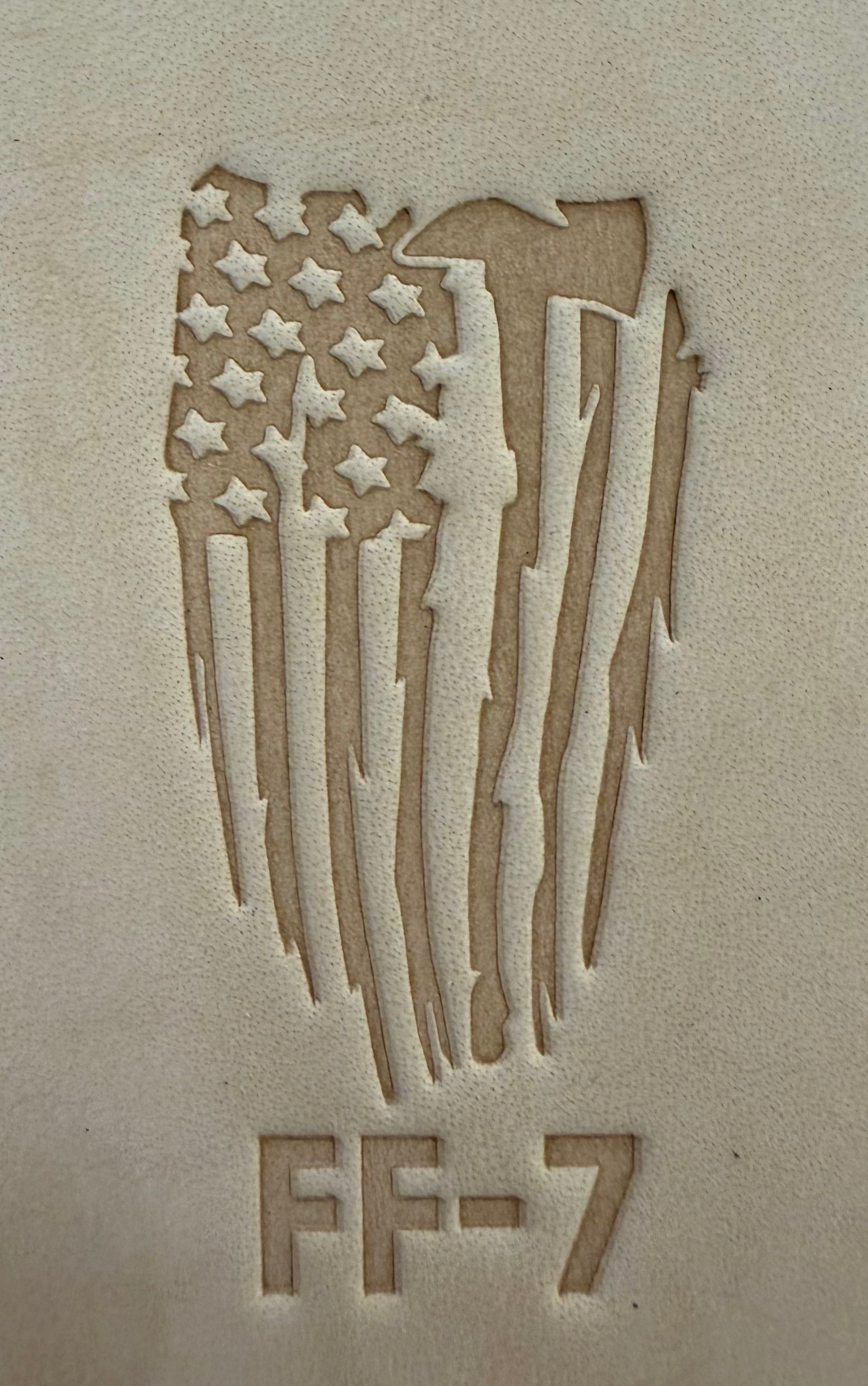 Delrin leather stamp pressing a tattered U.S. flag design with a firefighting axe and Halligan bar into leather.