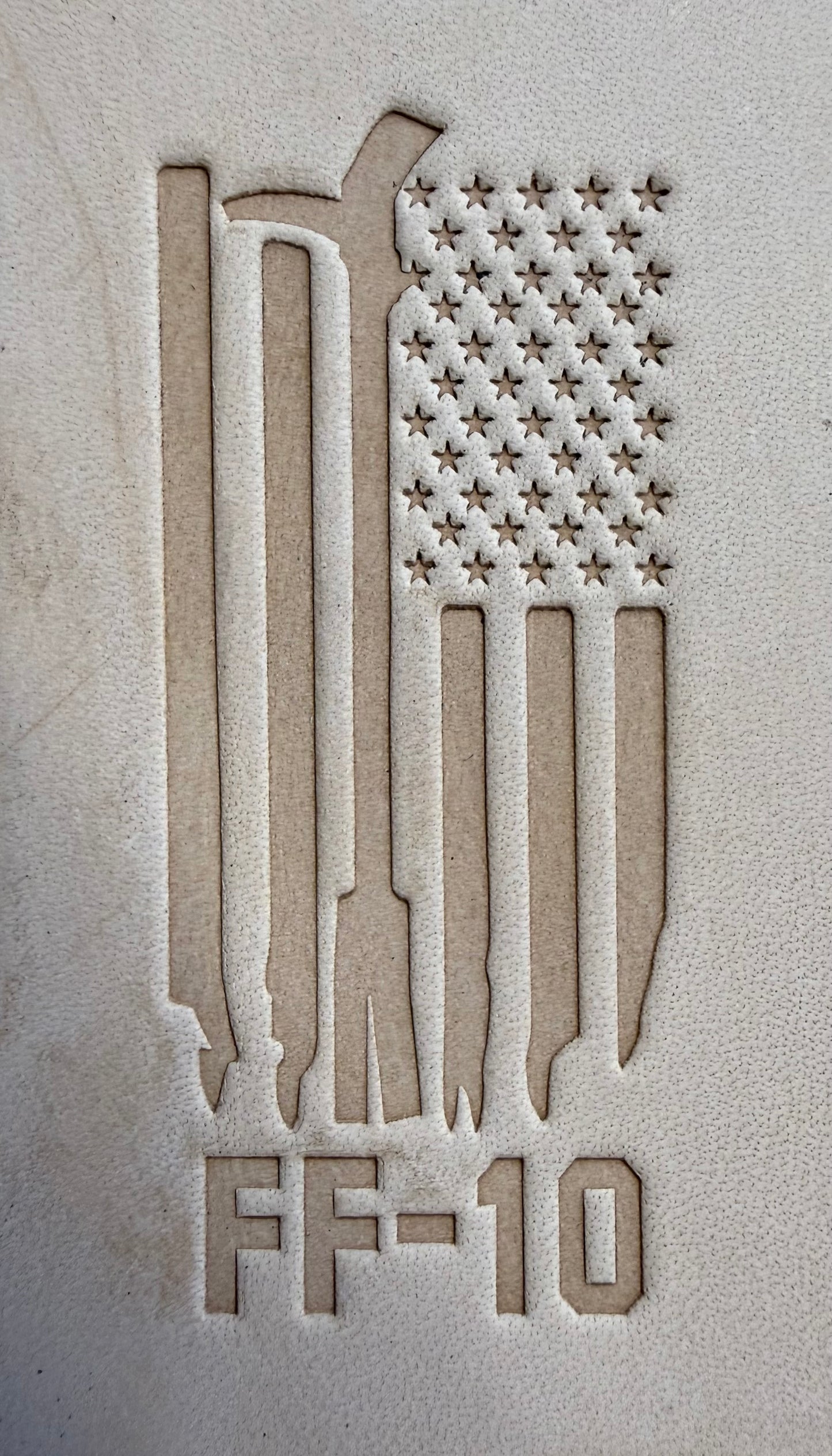Delrin leather stamp pressing a tattered U.S. flag design with a firefighting axe and Halligan bar into leather.
