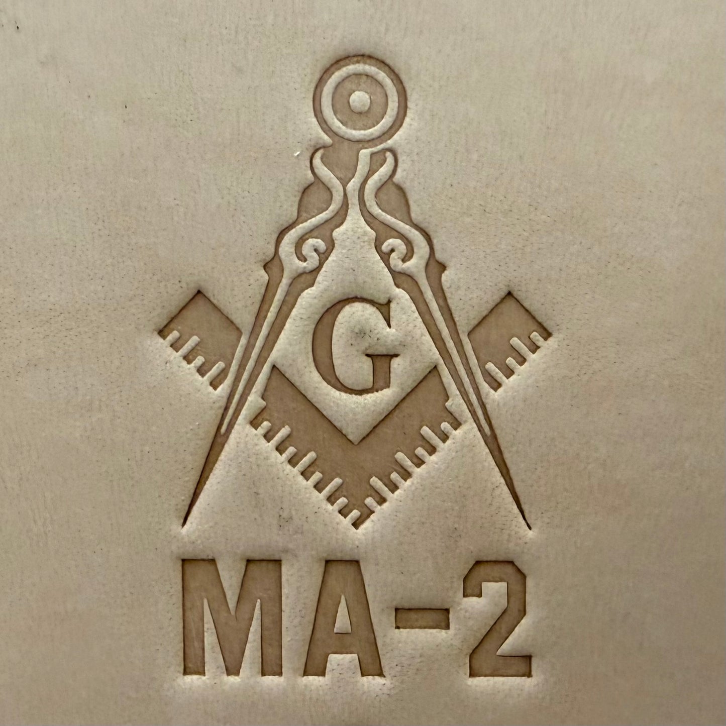 Embossing stamp featuring a Masonic square and compass emblem with the letter G.
