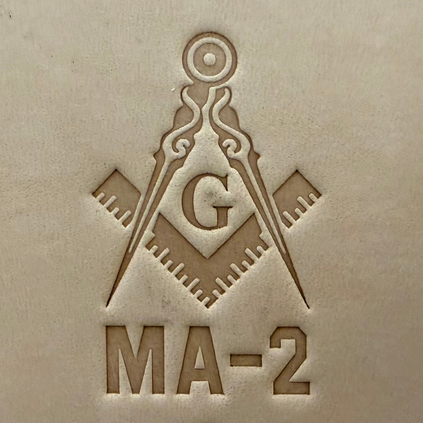 Embossing stamp featuring a Masonic square and compass emblem with the letter G.