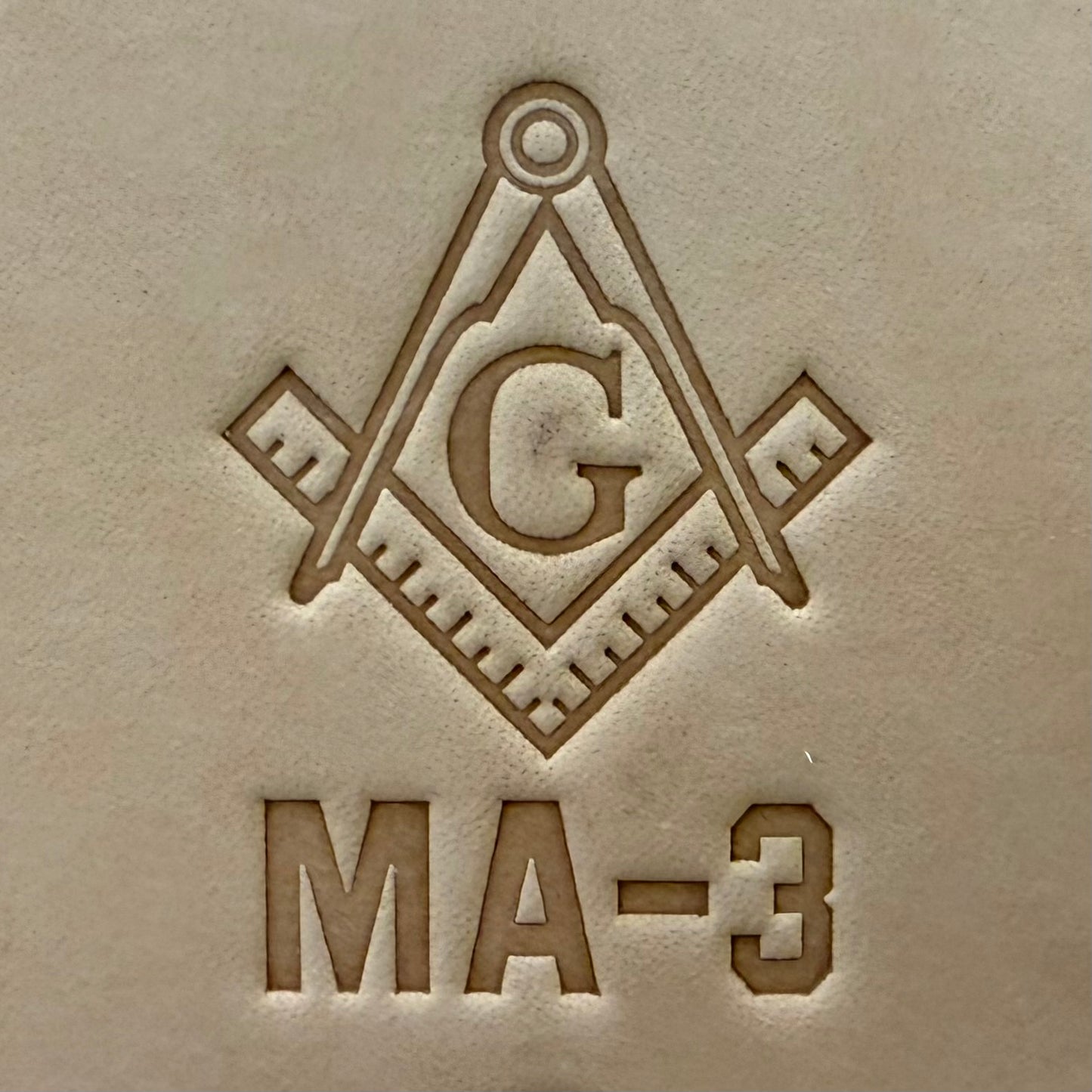 Embossing stamp featuring a Masonic square and compass emblem with the letter G.