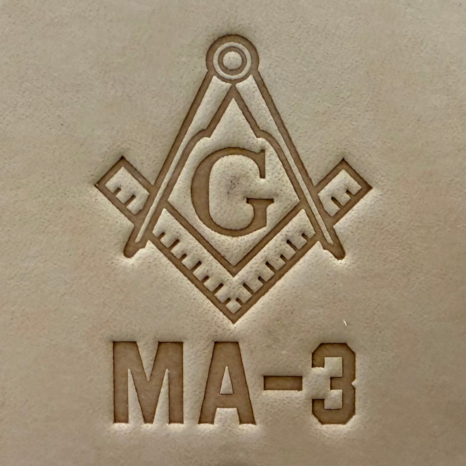 Embossing stamp featuring a Masonic square and compass emblem with the letter G.