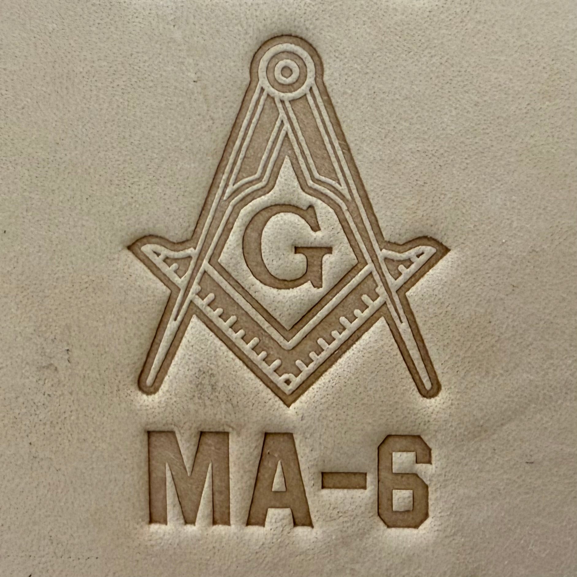 Embossing stamp featuring a Masonic square and compass emblem with the letter G.