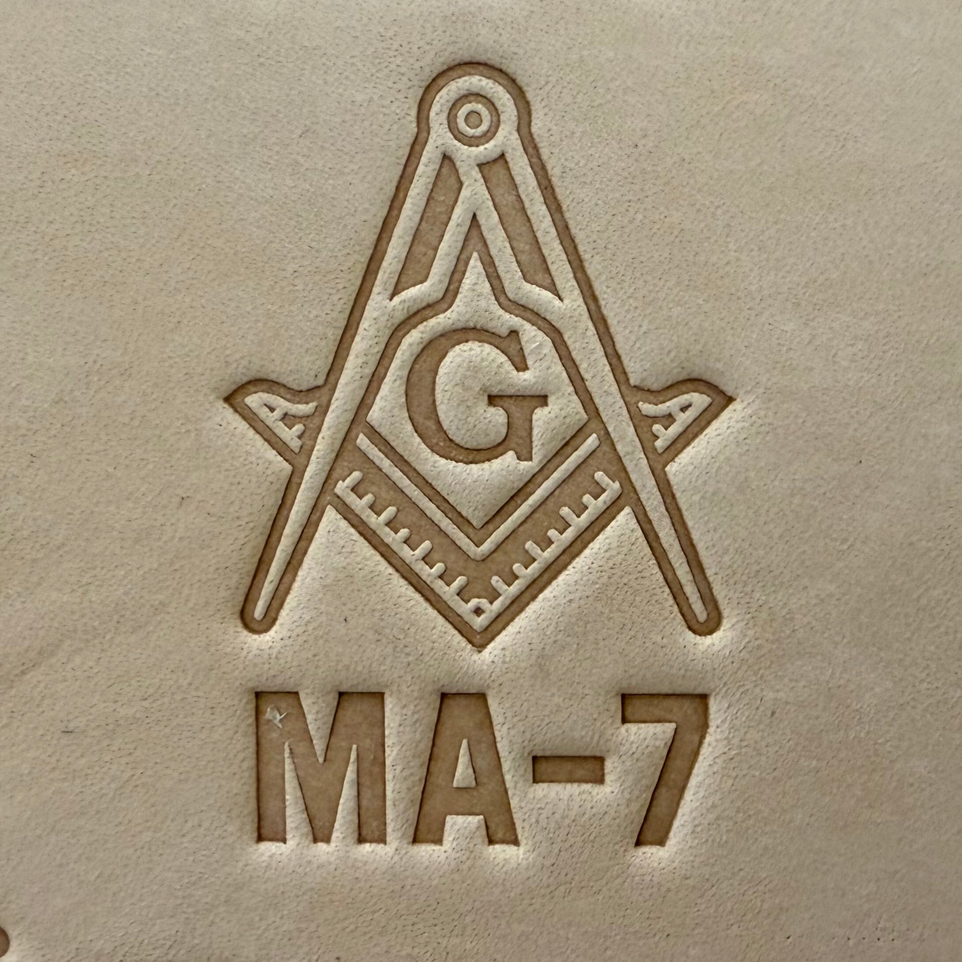 Embossing stamp featuring a Masonic square and compass emblem with the letter G.