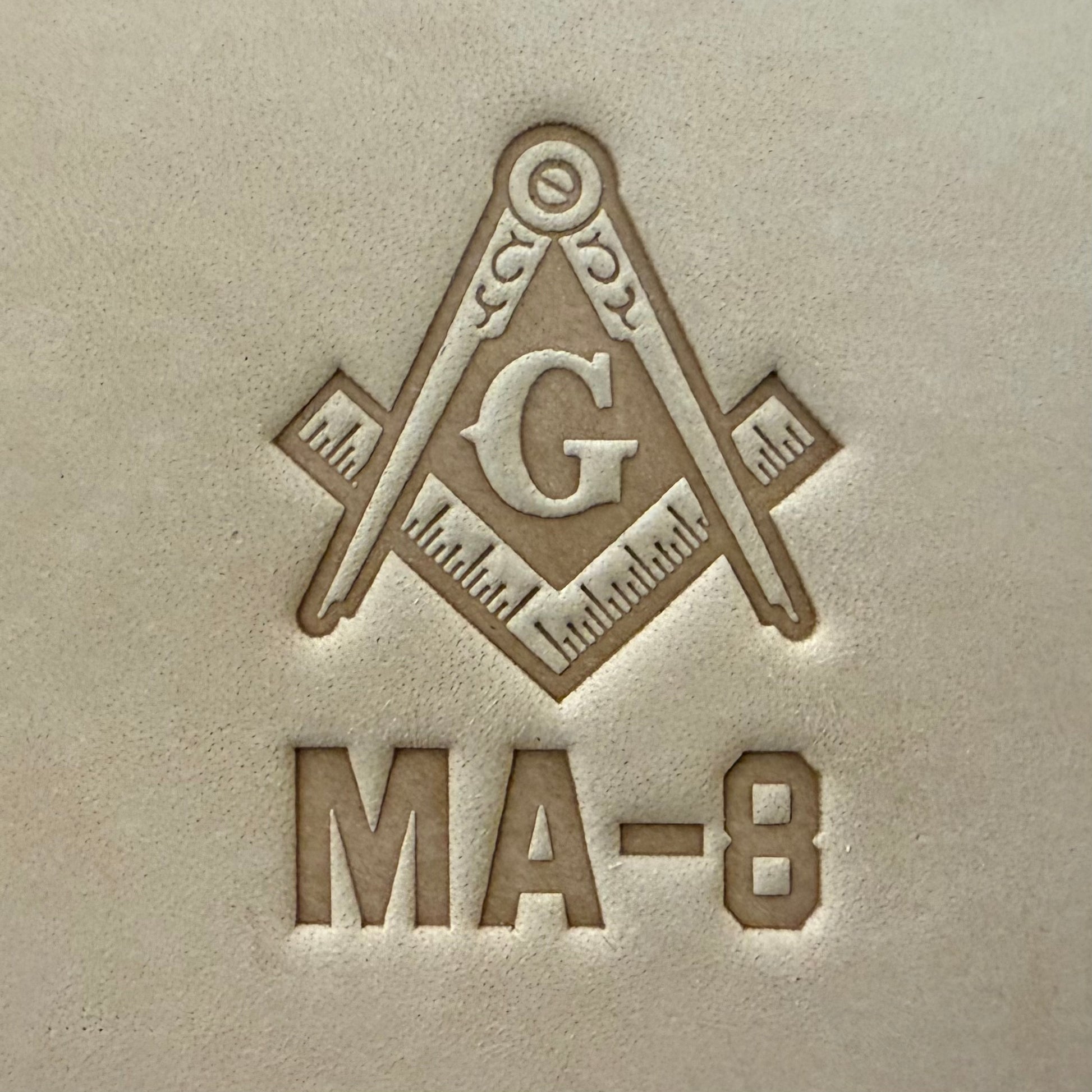 Embossing stamp featuring a Masonic square and compass emblem with the letter G.