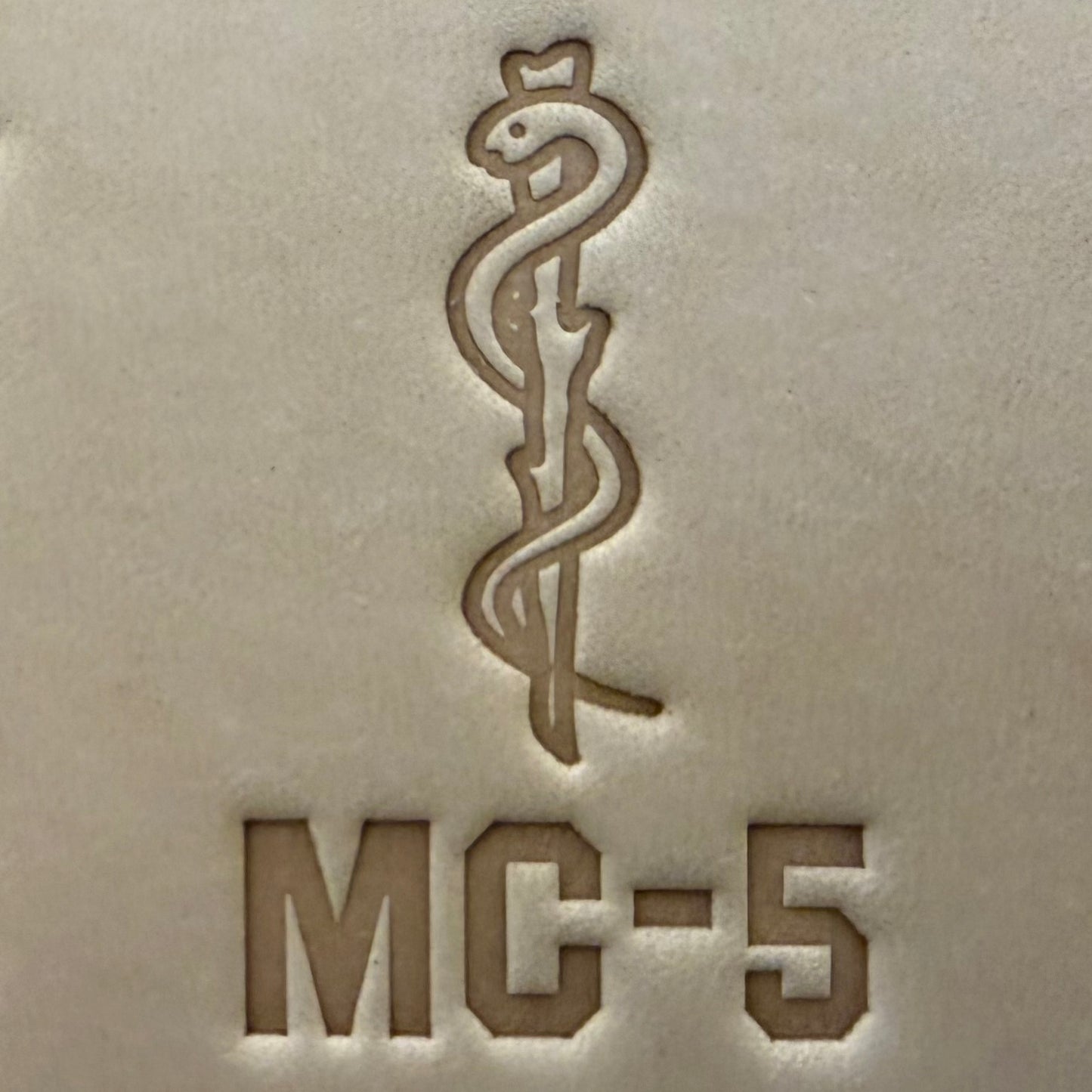 Leathercrafting impression of a medical caduceus symbol.