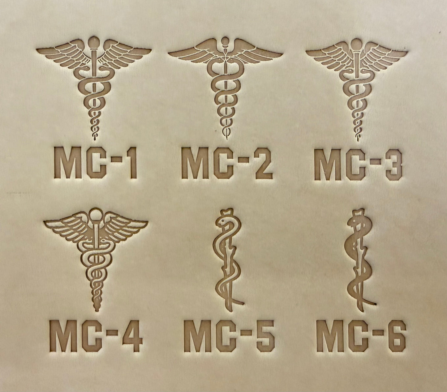 Leathercrafting impression of a medical caduceus symbol.
